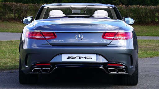 A Mercedes-Benz convertible parked near some grass.