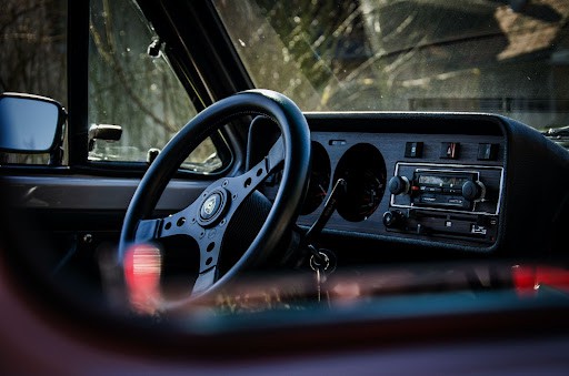 The interior of an older car with a key in the ignition. 