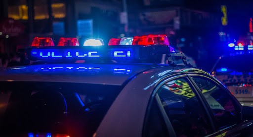 Two police cars with their lights on parked on a street at night.