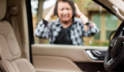  A woman looking through the window of her car and her keys are locked inside of it.