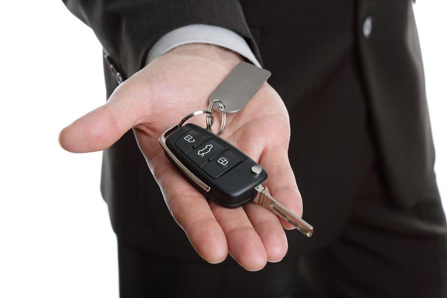 Car salesman or rental man giving over a car key