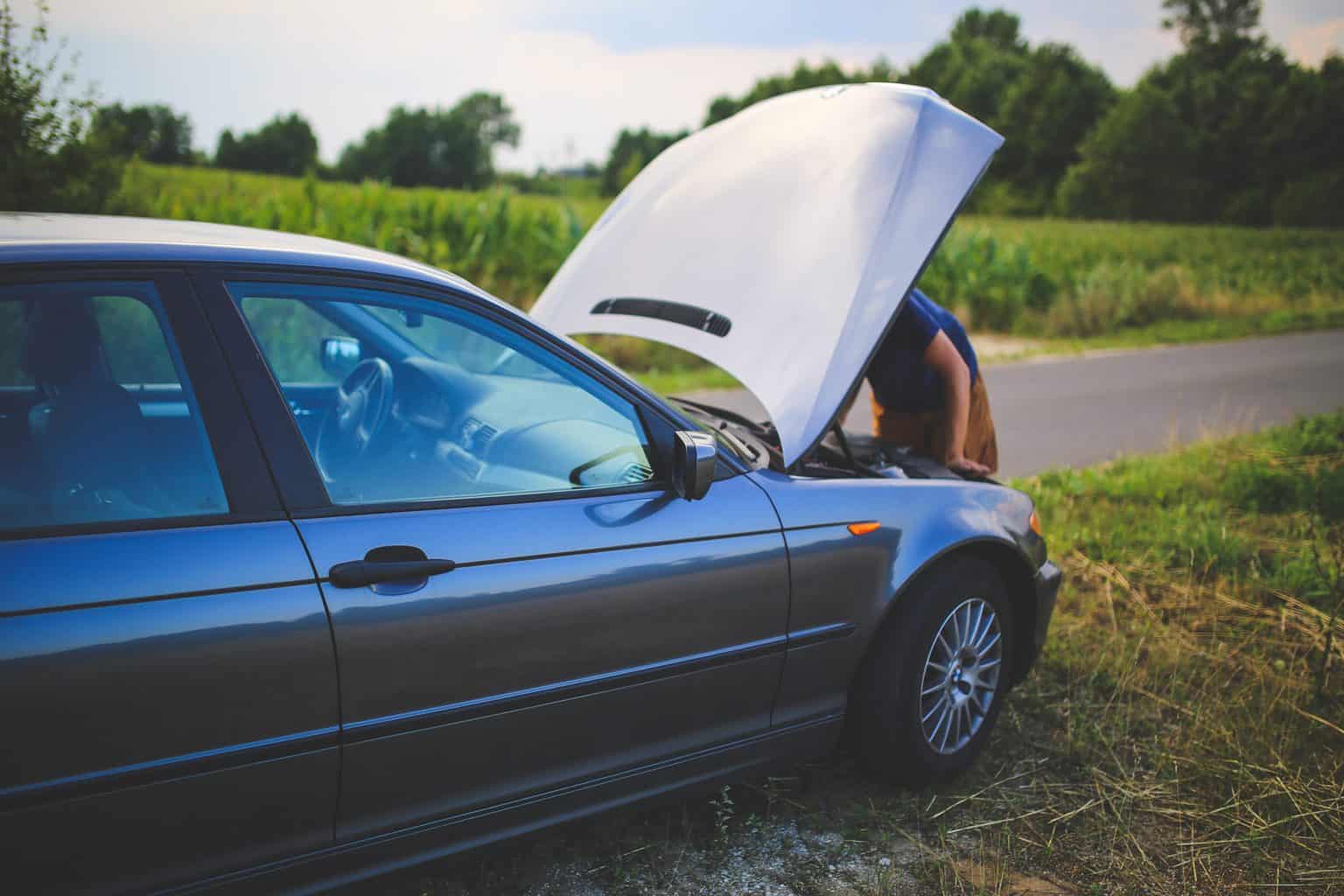 Broken down car with someone looking under the hood