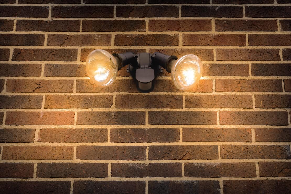 Two floodlights on a brick wall.