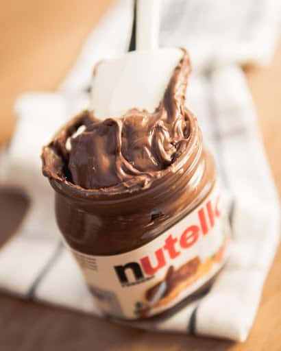 A jar of Nutella with a rubber spatula in it.