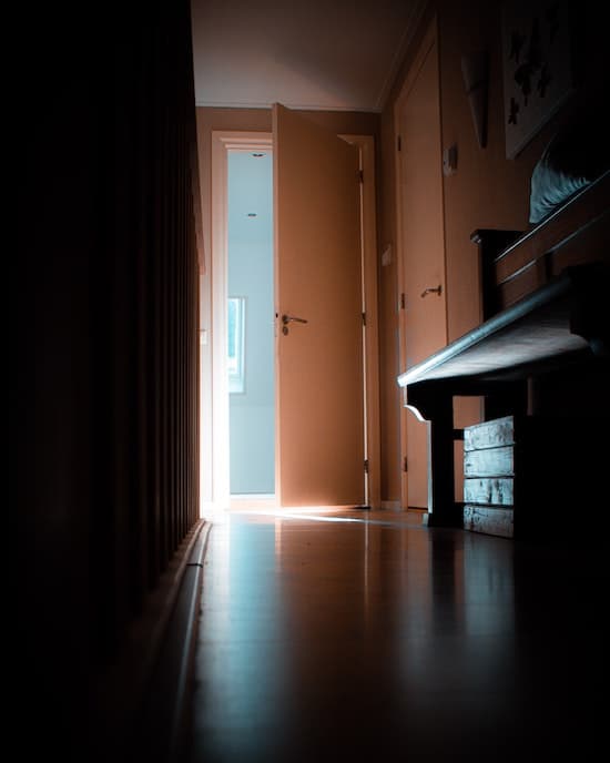 An open door at the end of a dim hallway.