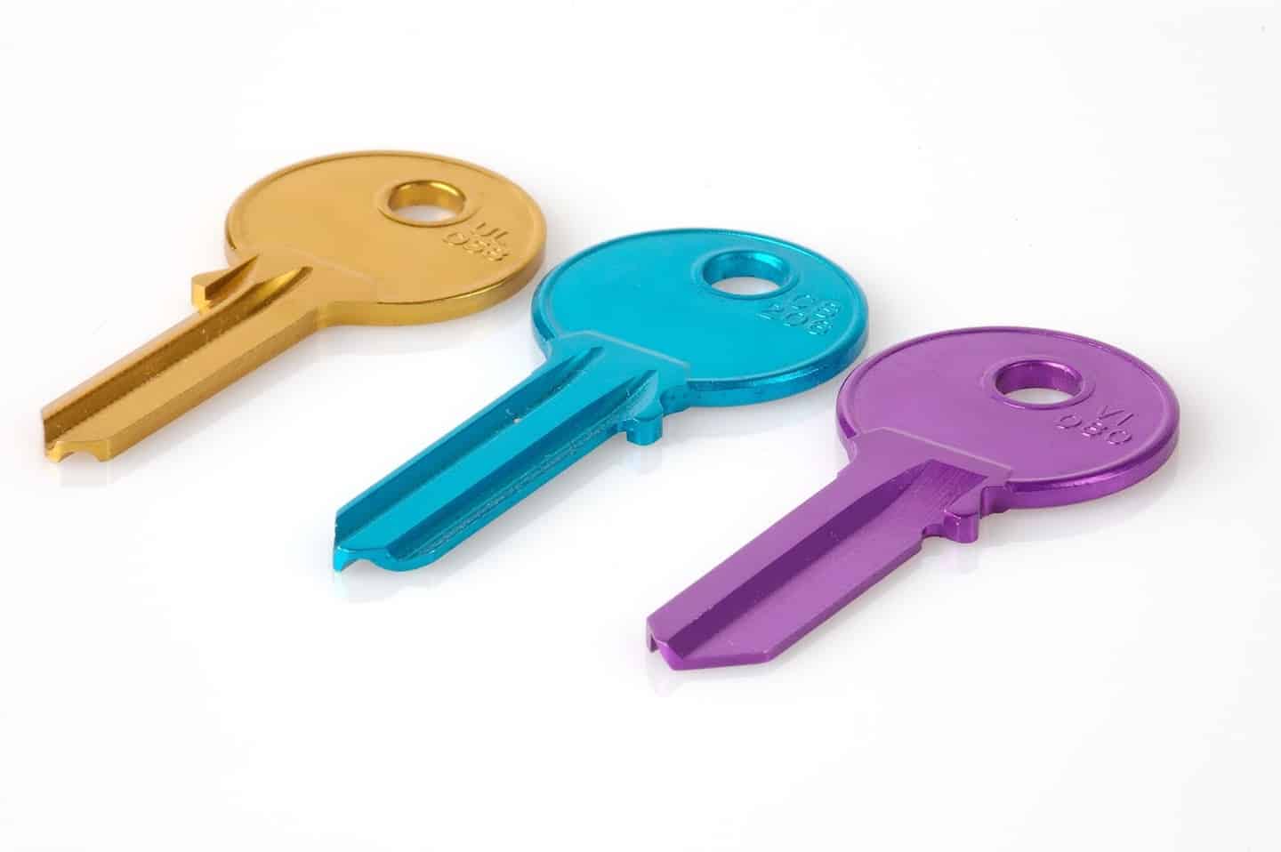 A yellow key, turquoise key, and purple key lying on a white background.