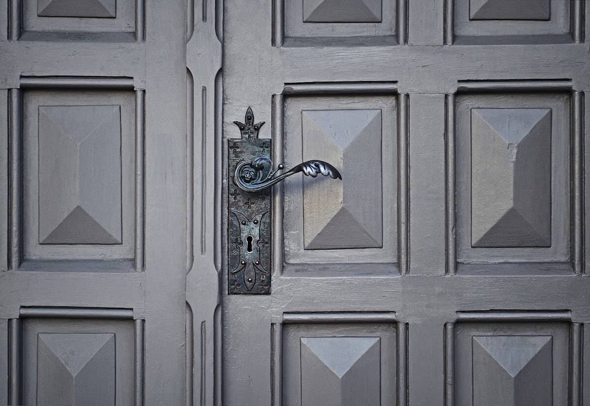 Lock with a swirled door handle on a grey door with geometric patterns.