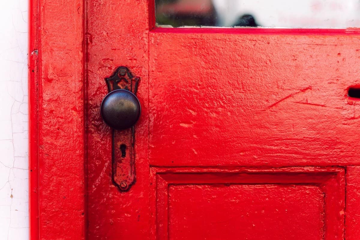 Simple lock and doorknob on a red door.