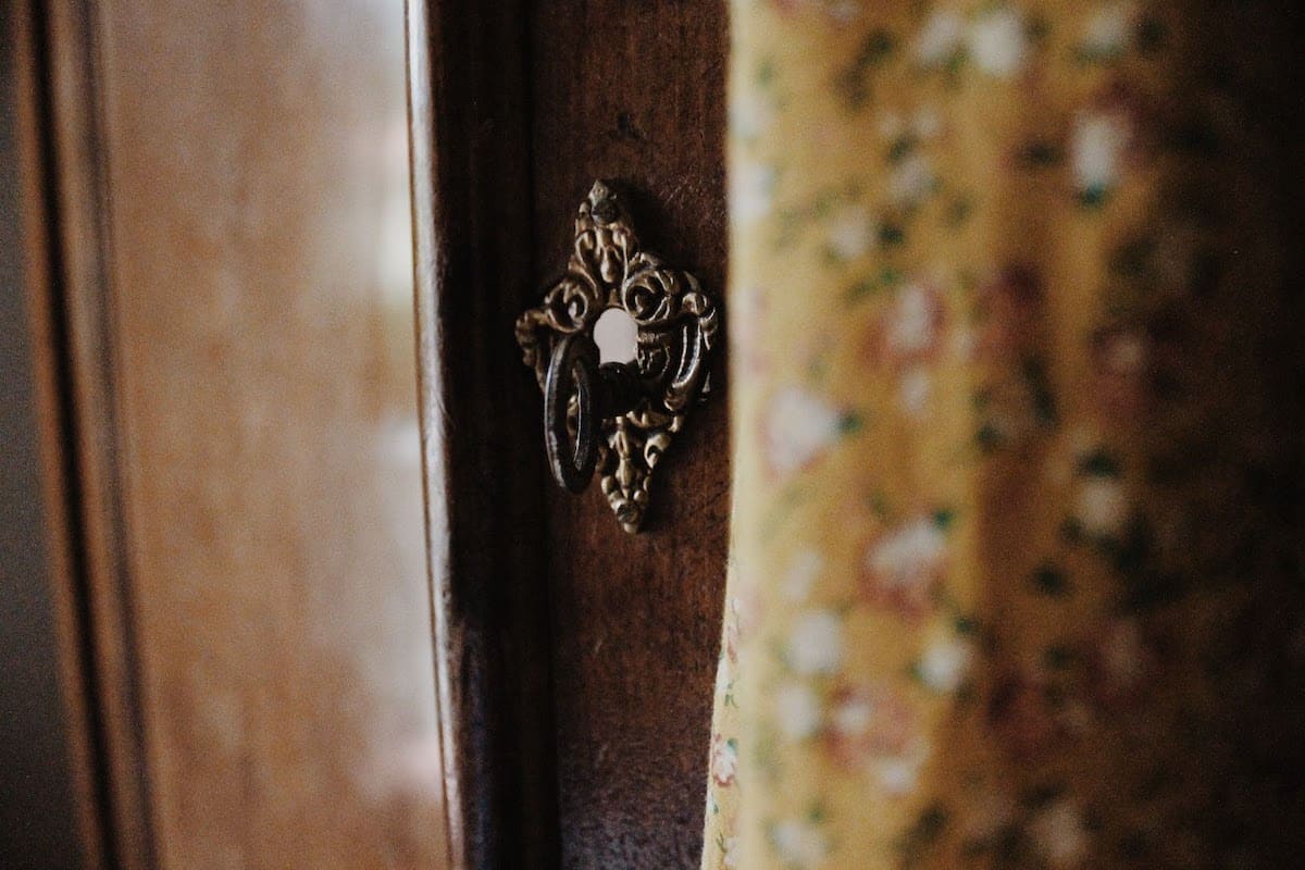 Skeleton key sticking out of an ornate lock on a door.