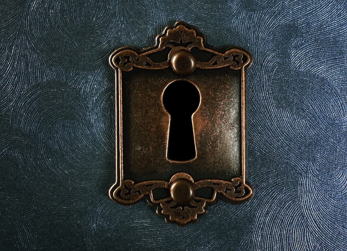 Decorative brass keyhole on a blue textured background.