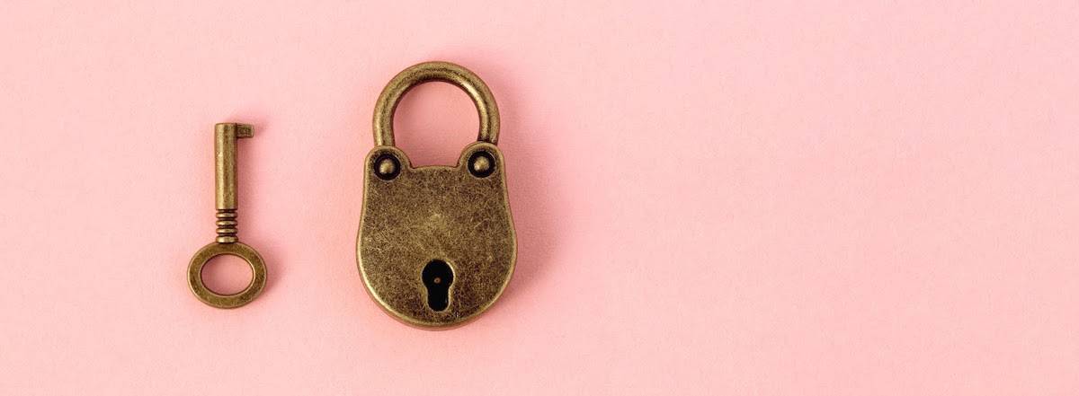 A simple brass padlock next to a matching key on a pink background.