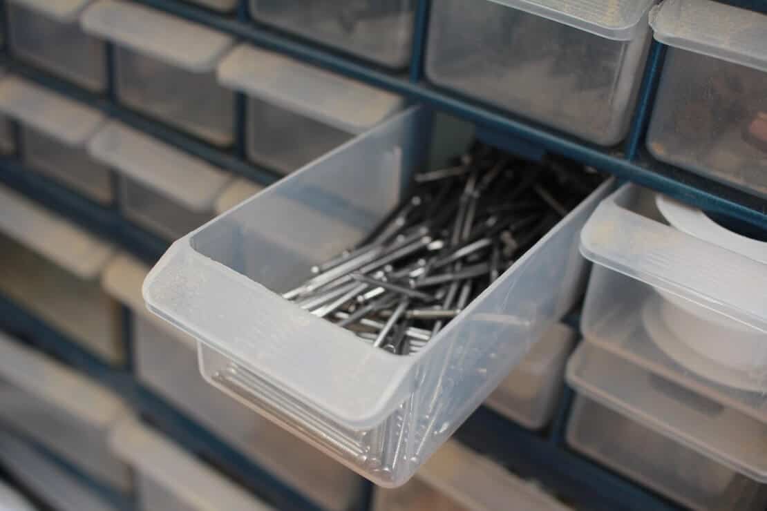Small plastic organizing drawers; one is open and has nails in it.