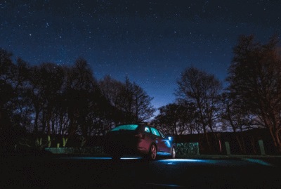 A car with the lights on parked in darkness.