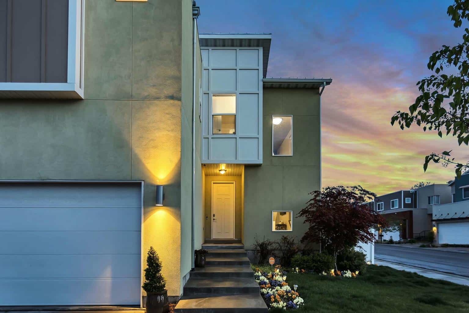 The outside of a house with outdoor lamps lighting the way.