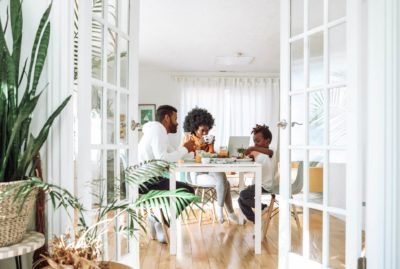 A family of three sitting around a white table.