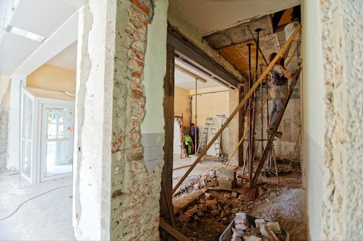 A photo of a home being renovated with exposed walls and a man on a ladder.