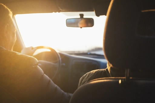 An interior shot of two people driving in a car at sunset.