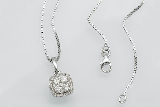 A diamond necklace on a plain gray background. 