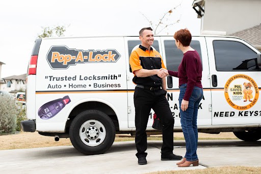 Locksmith technicians shaking hands with a customer while they stand in front of a Pop-A-Lock van.