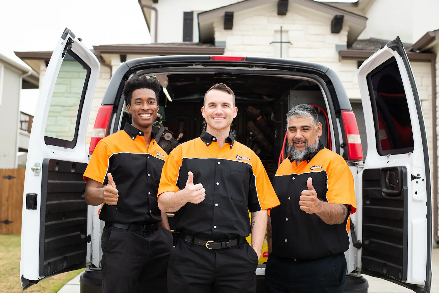 Three locksmith technicians from Pop-A-Lock Metairie standing next to their van holding thumbs up.