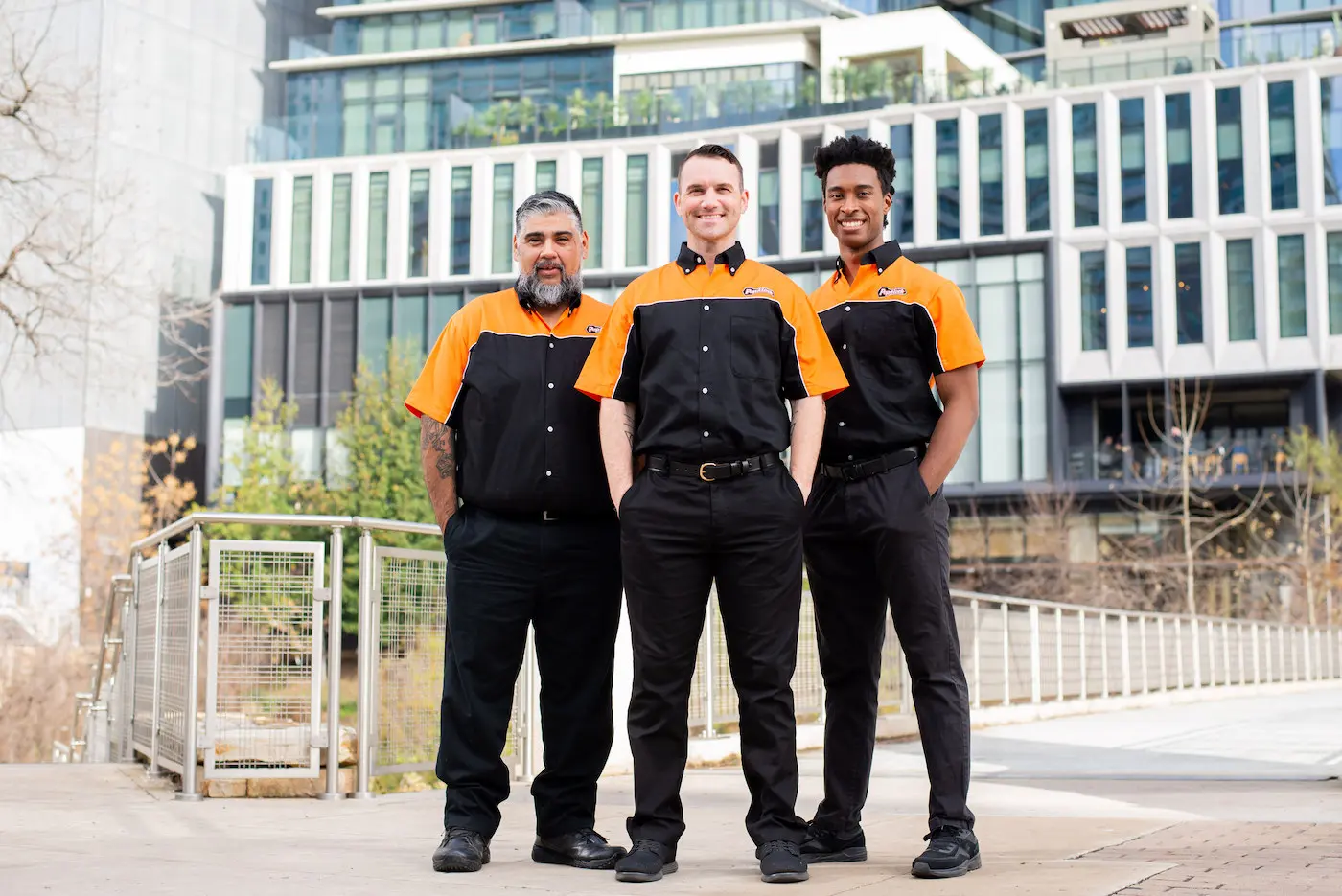 Three commercial locksmith technicians from Pop-A-Lock Metairie standing in front of an office building in the city.