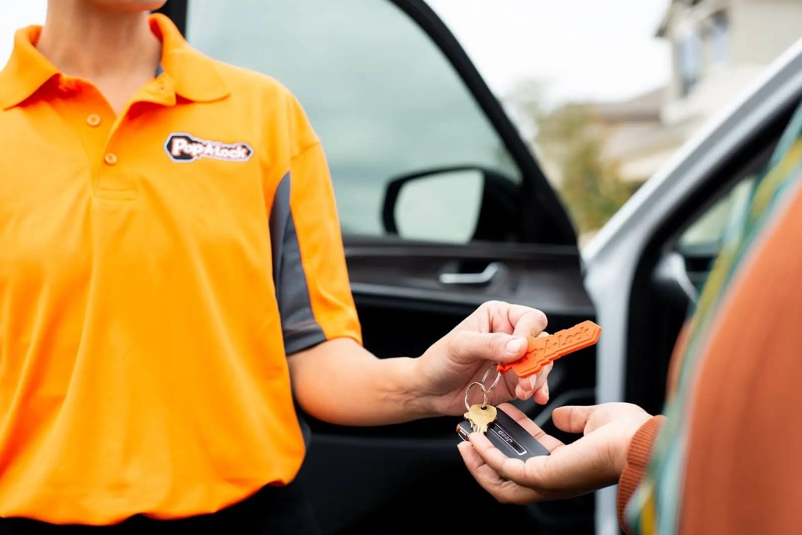 Pop-A-Lock Tulsa technician handing customer a car key replacement.