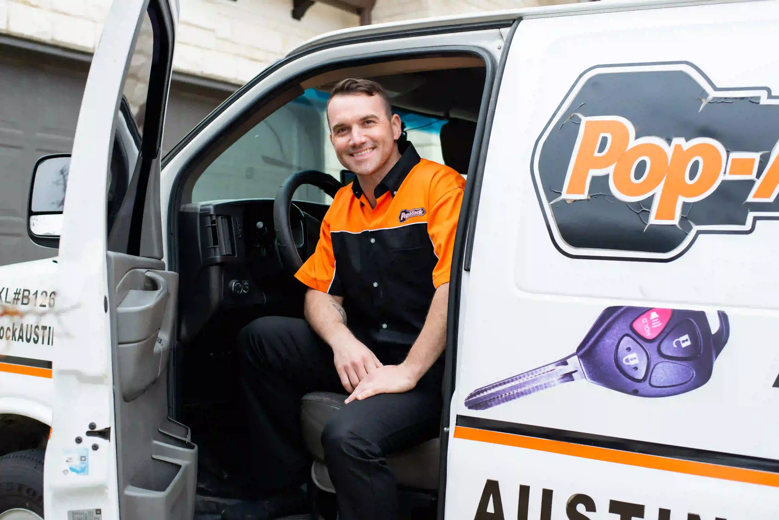 Pop-A-Lock technician sitting in service vehicle wearing branded uniform.