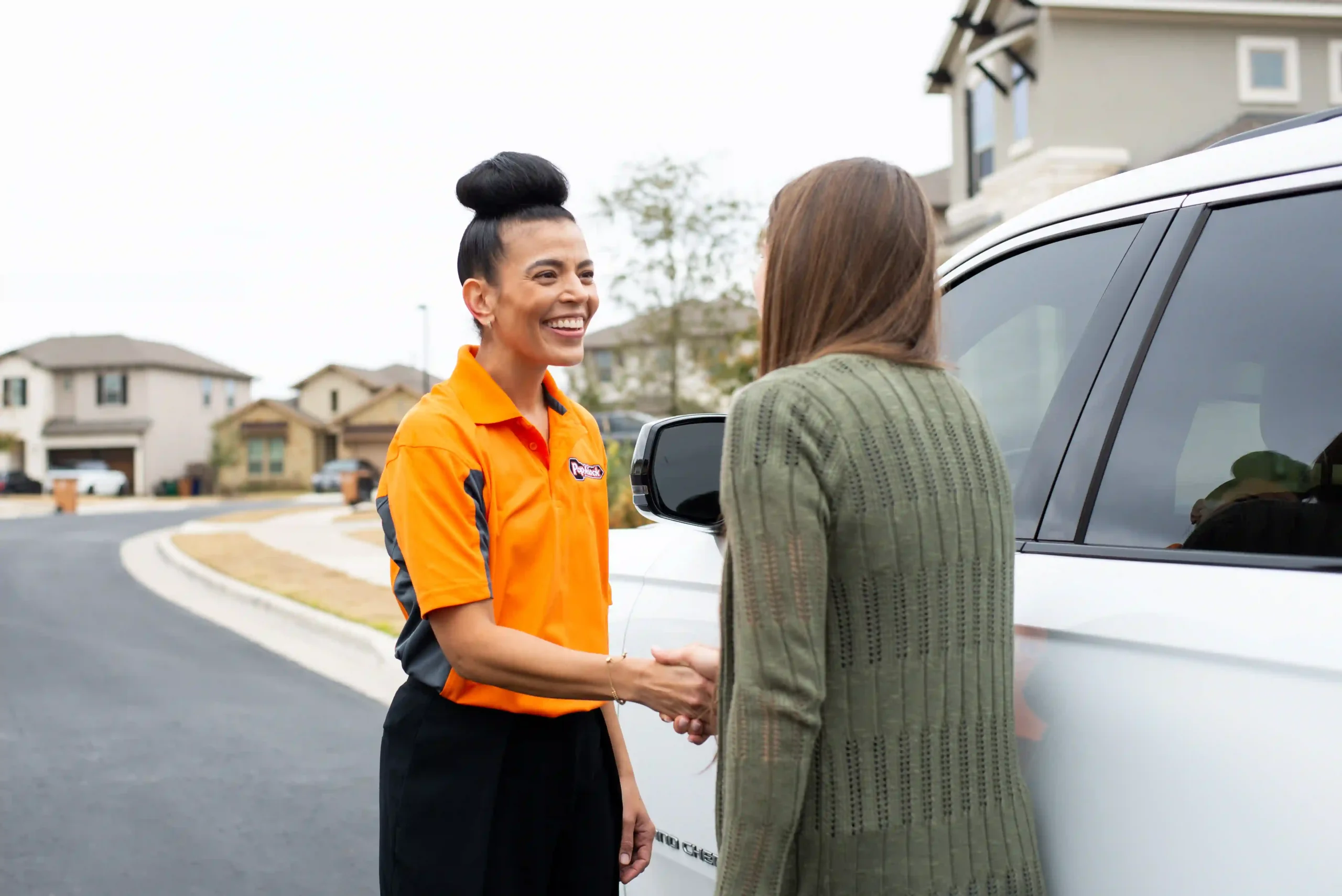 Pop-A-Lock technician shaking hands with woman locked out of car.