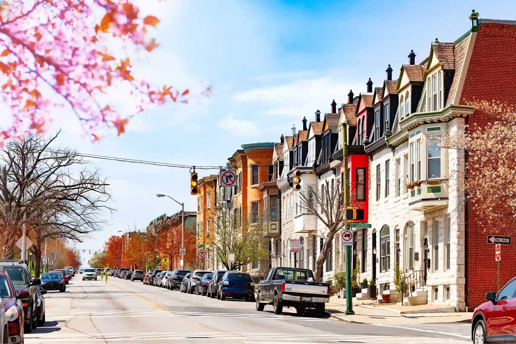 Residential street in Baltimore, Maryland, lined with cars on either side.