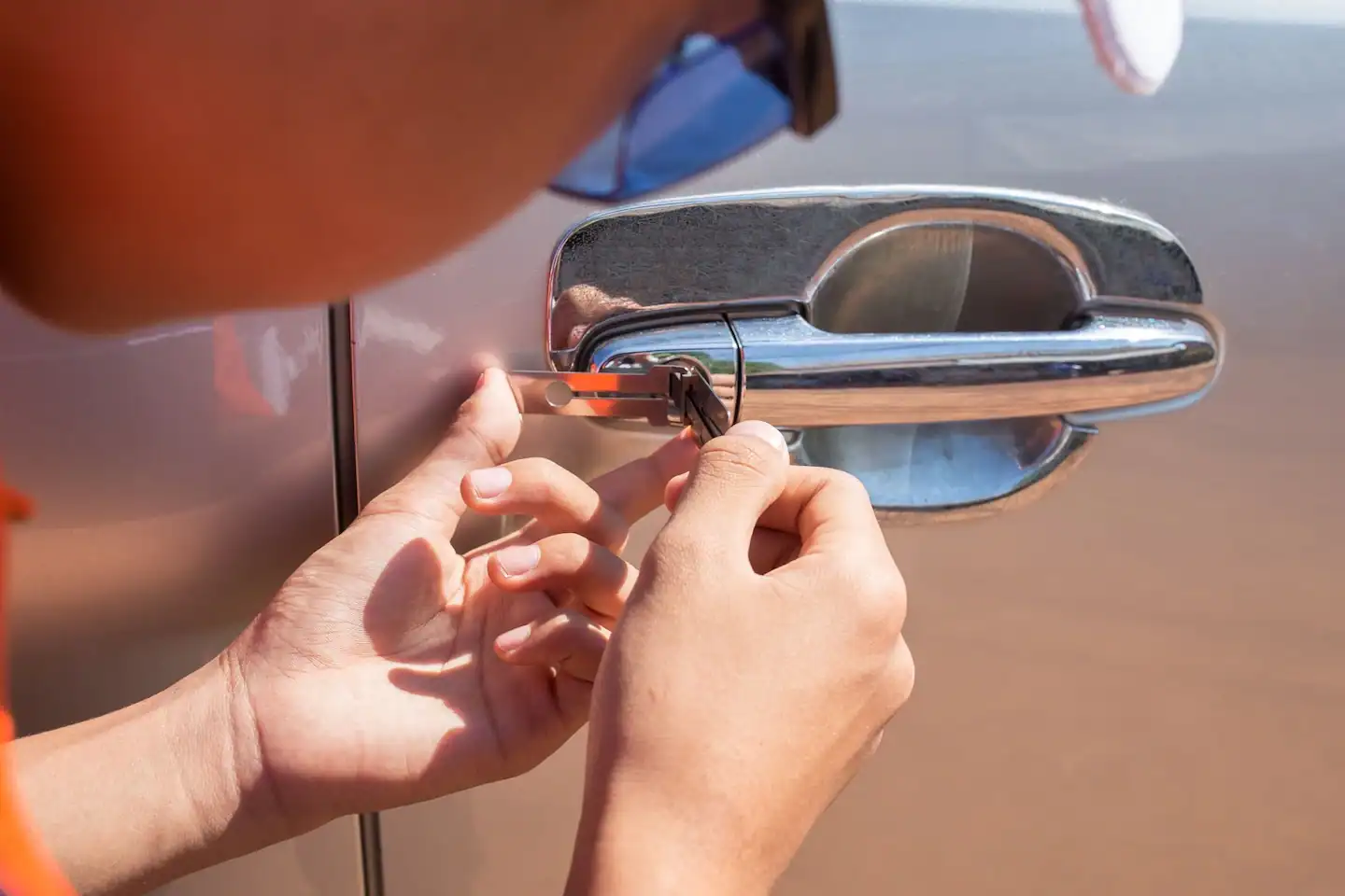 Locksmith opening a locked car door using a lockpicker.
