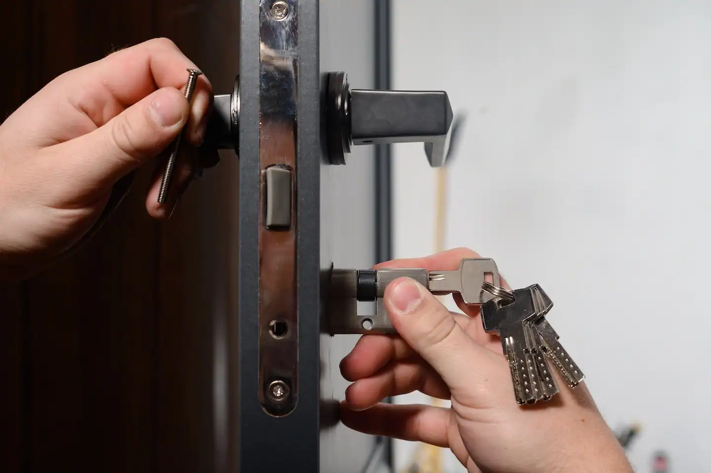 Locksmith installing a new deadbolt and door handle set with keys in hand