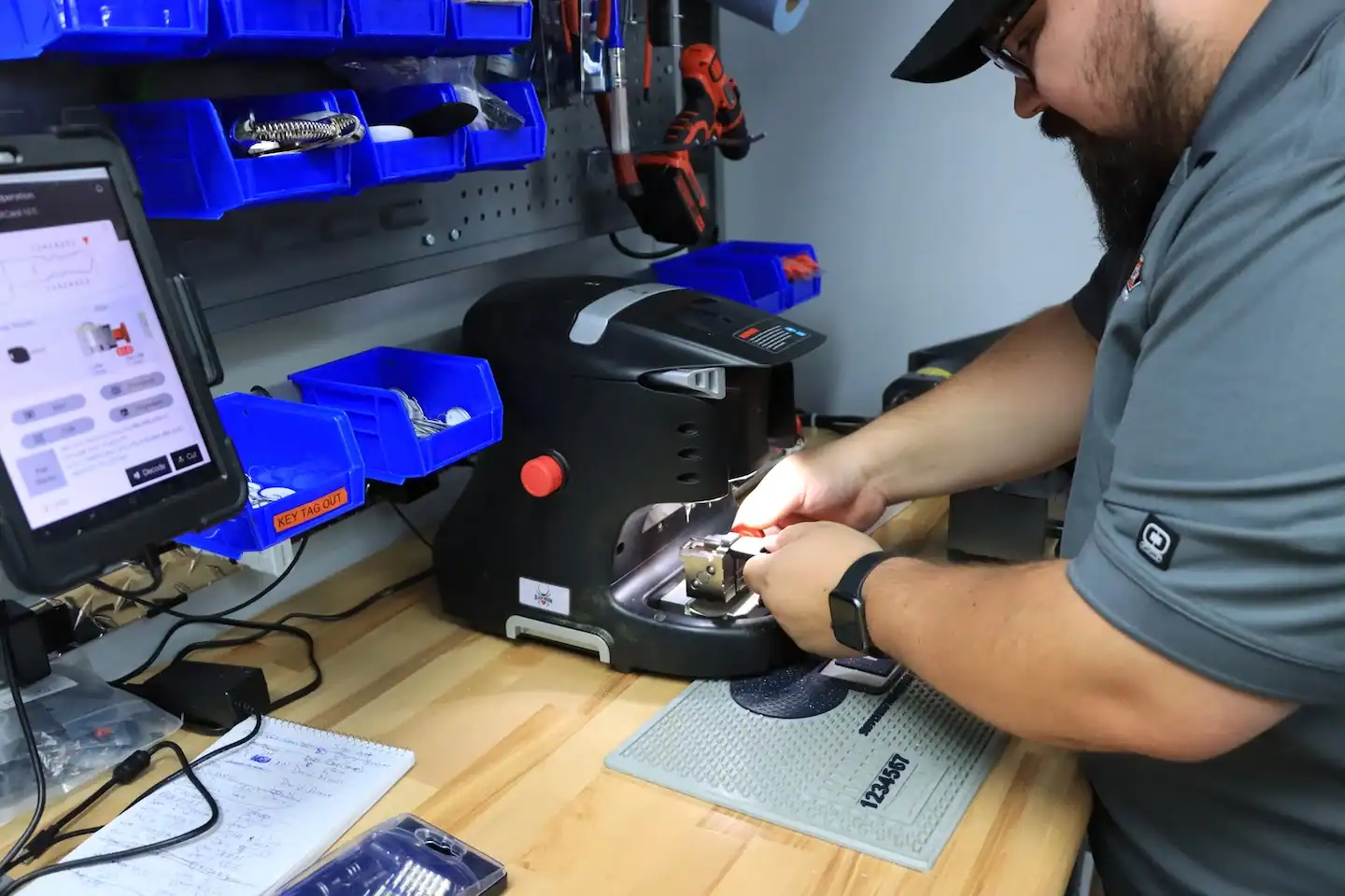Locksmith technician cutting a key on a key-cutting machine at a workbench
